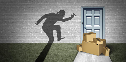 Shadow of a person sneaking towards a stack of cardboard boxes in front of a blue door on a brick wall background.